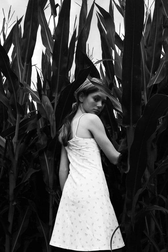 Photographie en noir et blanc montrant Nina éclairée par une lumière naturelle contrastée, avec des ombres marquées sculptant son visage et son expression.